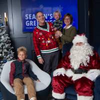 Parents with two boys smile with Santa
